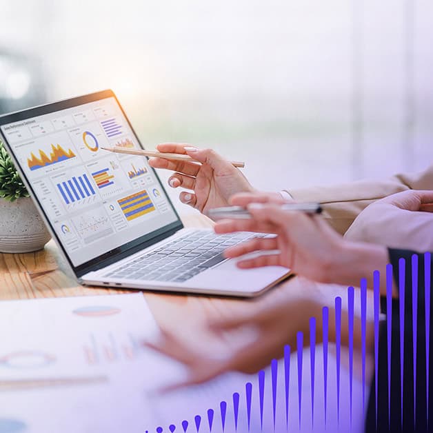 Two sets of hands gesturing toward an open laptop with a dashboard of graphs on it