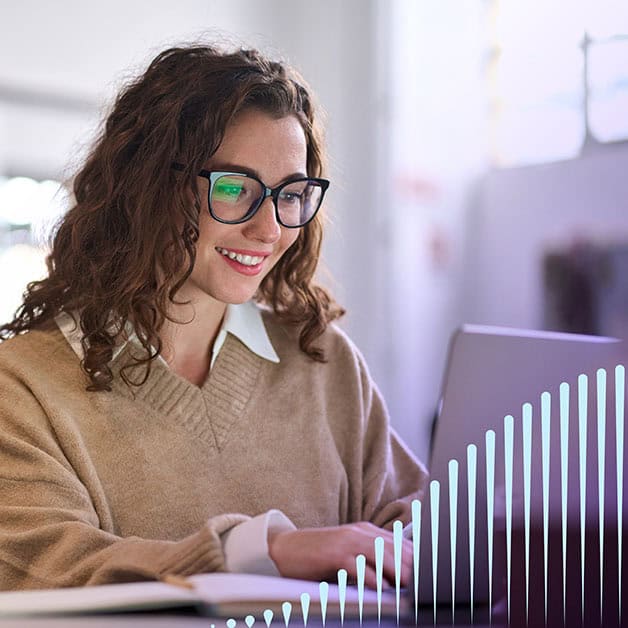 Woman with glasses smiling and typing on laptop