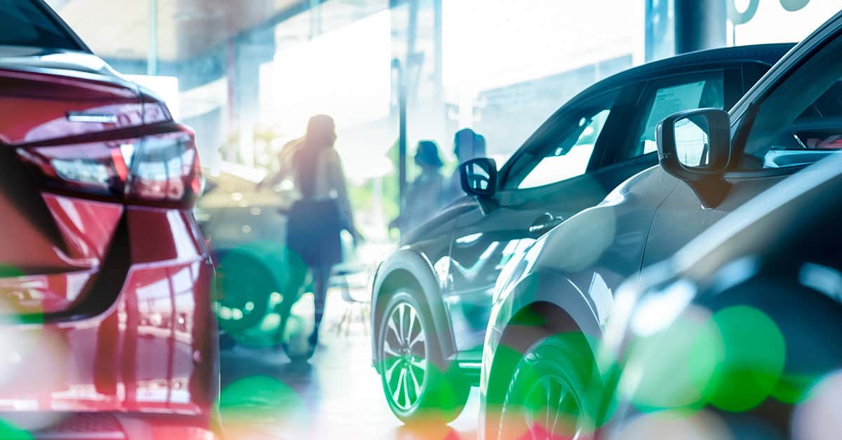 Cars in a showroom with people standing near them