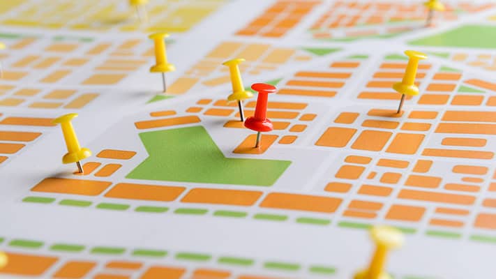 Orange and green map with yellow and red pins in it