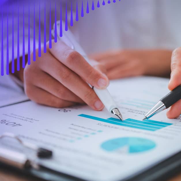 Closeup of hands holding pens and pointing at graphs
