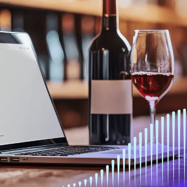 Laptop with wine glass and bottle beside it
