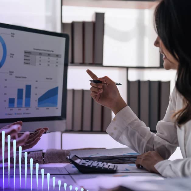 Woman smiling and pointing to a computer screen with charts and graphs on it