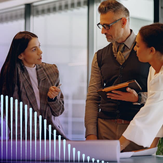 Two women and a man talking in an office
