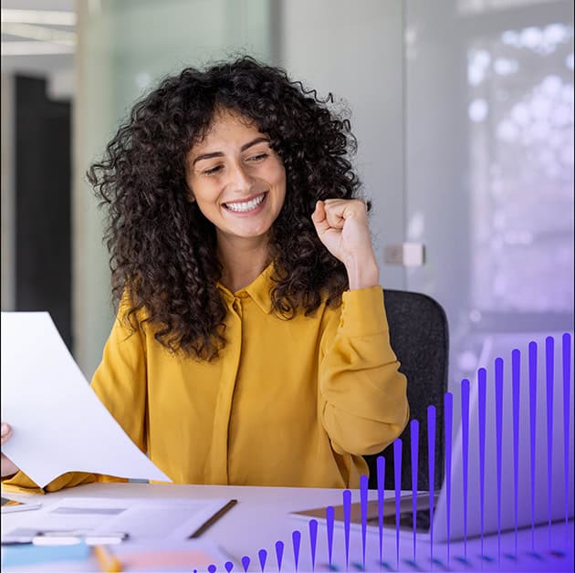 Woman smiling and holding a sheet of paper at a desk
